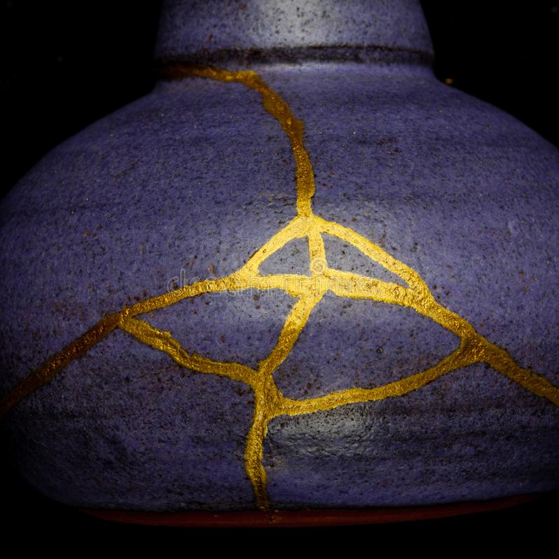 A blue kintsugi vase, the cracks filled with gold.
