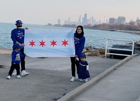 Samad Abdul and his family hold the Chicago flag while posing in front of Lake Michigan and the city skyline. The Rohingya family -- Samad in a ball cap, his wife in a black hijab, and their two American-born toddlers -- are all wearing Cubs gear.